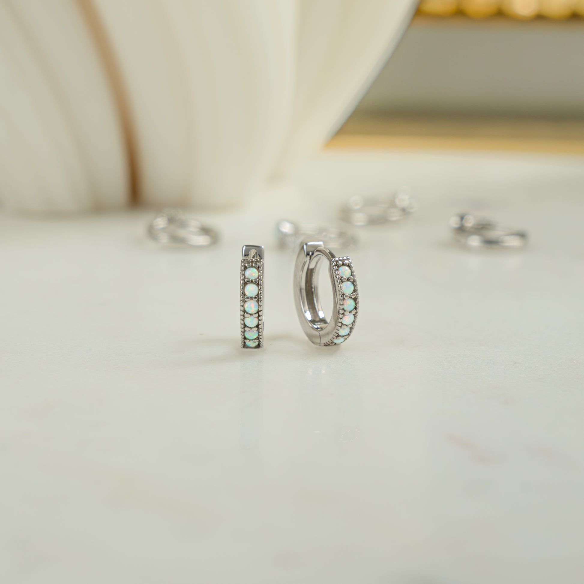 Close up image of dainty sterling silver huggie earrings. The opal huggie earrings are a perfect October birthstone gift for her. 