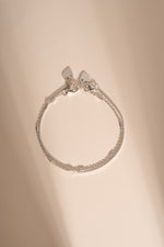 Silver box chain and satellite bracelets arranged together on a cream background.