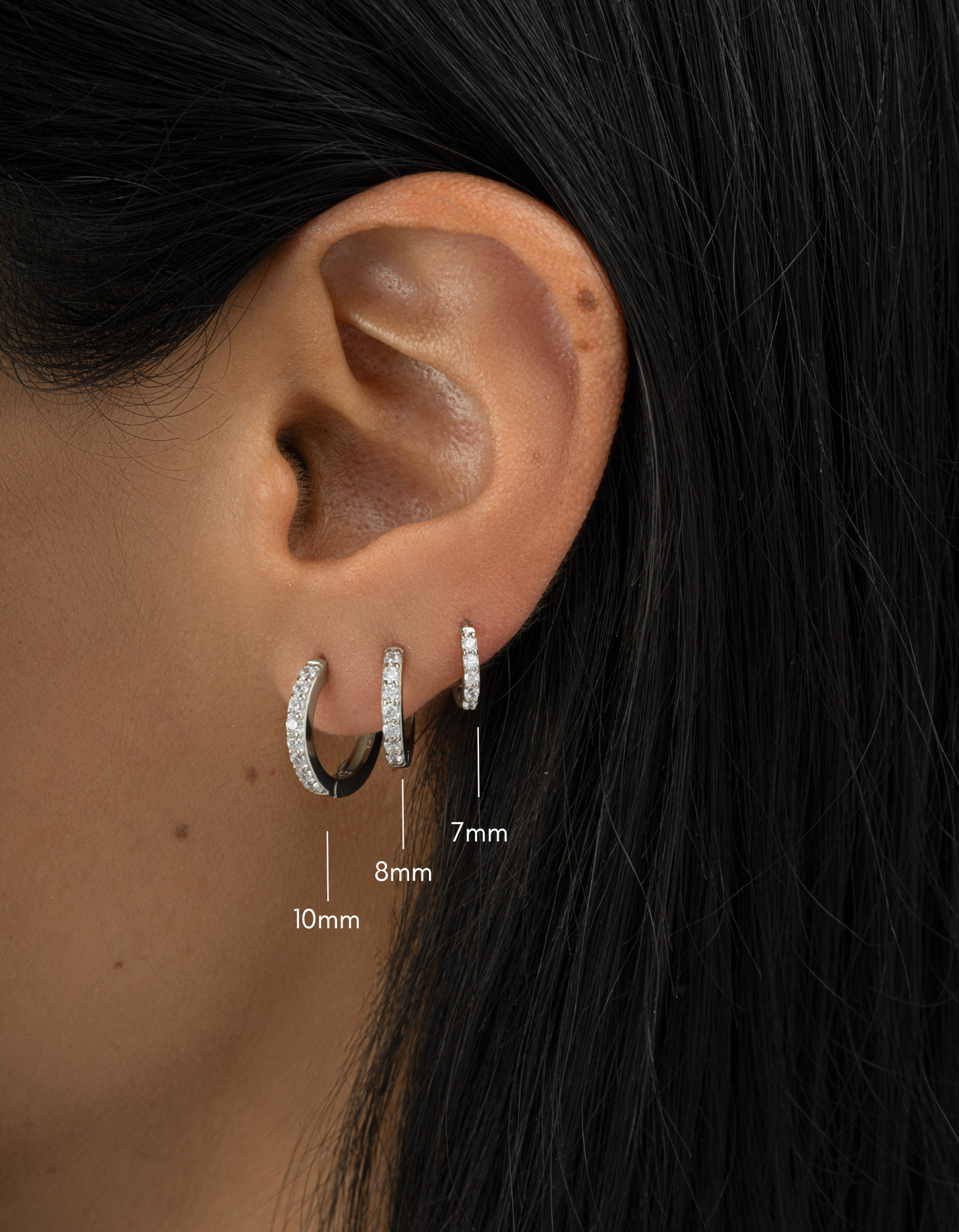 sterling silver earring stack with 7mm studded huggie, 8mm huggie, 10mm huggie with cubic zirconia stones earring stack on model