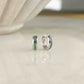 a pair of sterling silver tiny hoop earrings featuring a striped emerald band down the center