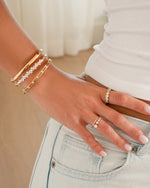 Gold Sami Jewels studded bangle bracelet stacked on a model's wrist, showcasing textured metal and stylish design.