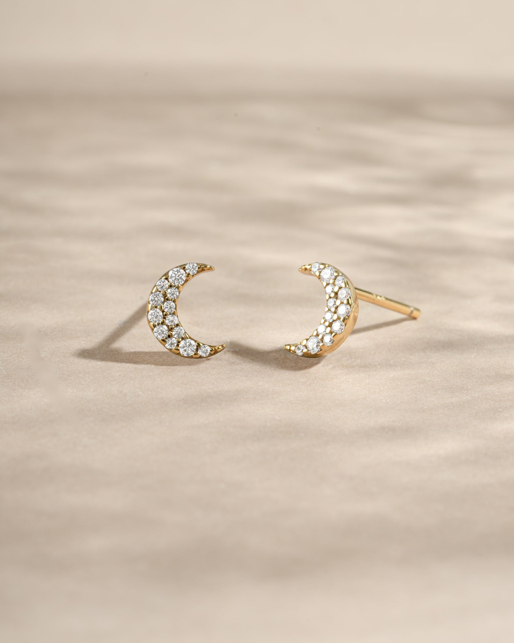 Gold studded moon earrings by Sami Jewels, featuring small crescent-shaped studs with metallic accents and a sleek design.