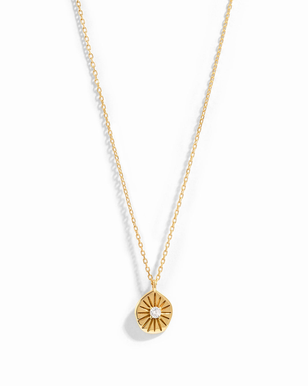 Gold Sunburst Medallion Necklace by Sami Jewels displayed on a white background, showcasing its intricate sunburst design.