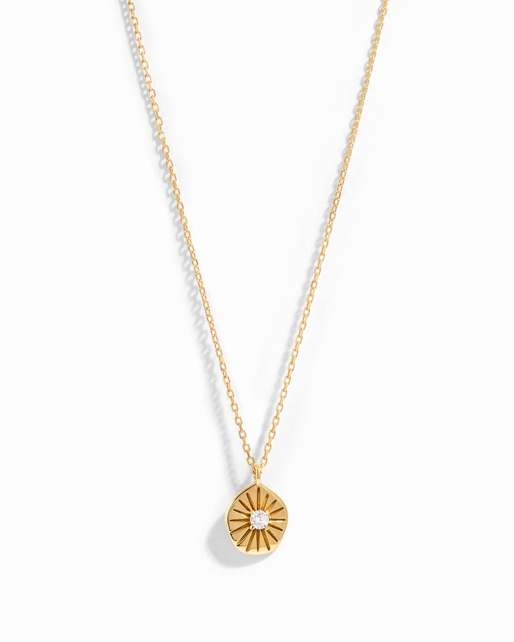 Gold Sunburst Medallion Necklace from Sami Jewels featuring a detailed sunburst pendant on a chain.