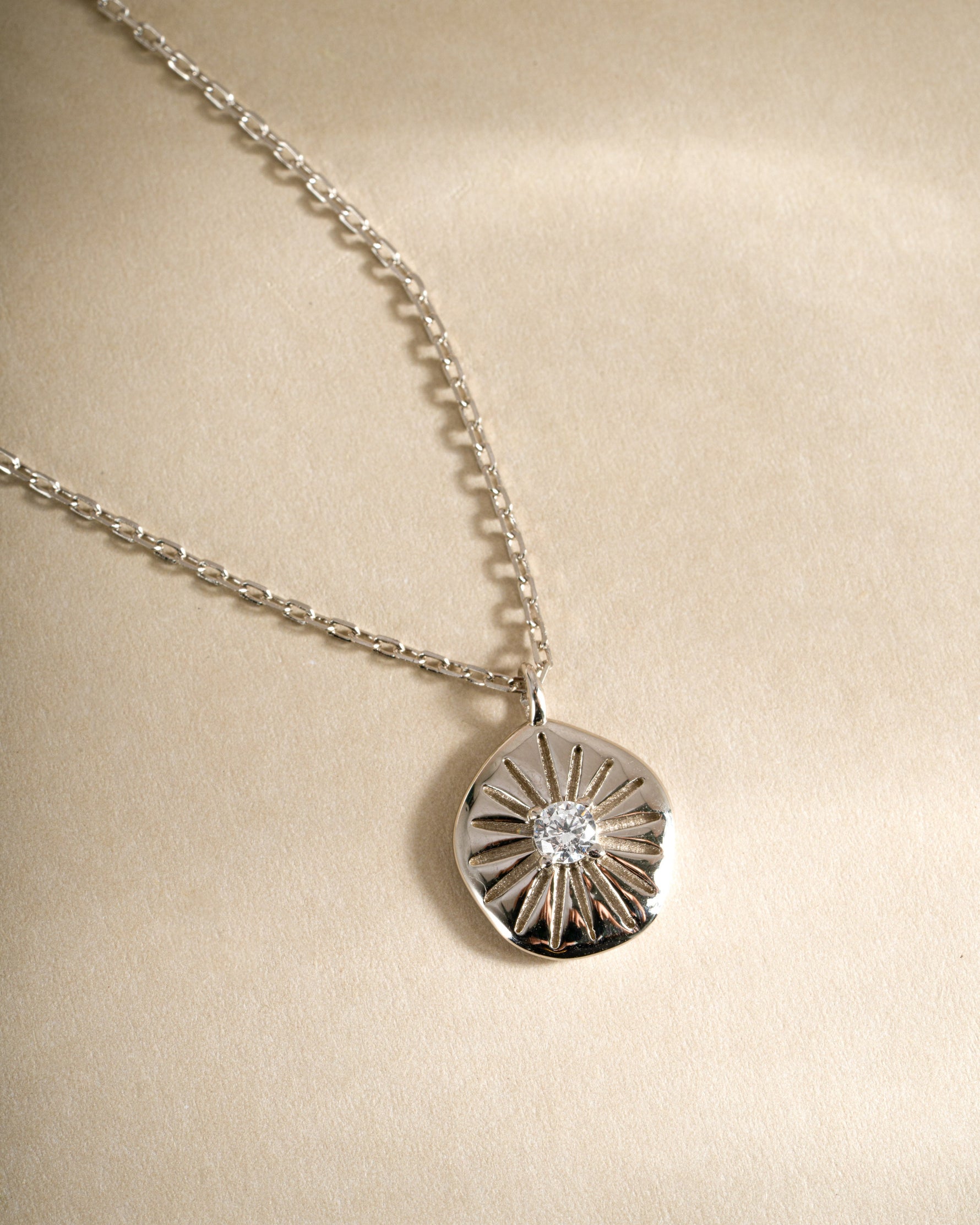 Close-up of Sami Jewels Sunburst Medallion Necklace featuring a sterling silver sunburst pendant on a delicate chain.