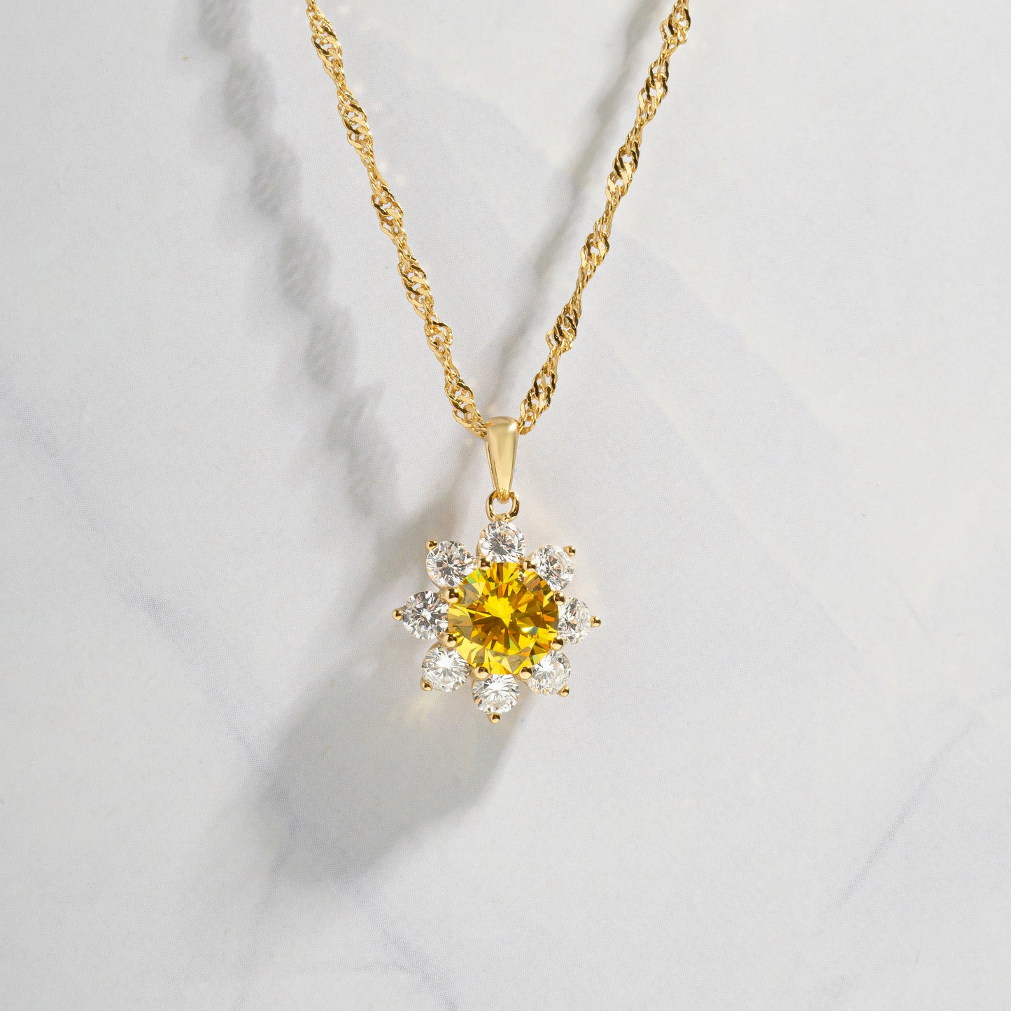 image against a marble backdrop of a sunflower pendant necklace with a citrine stone