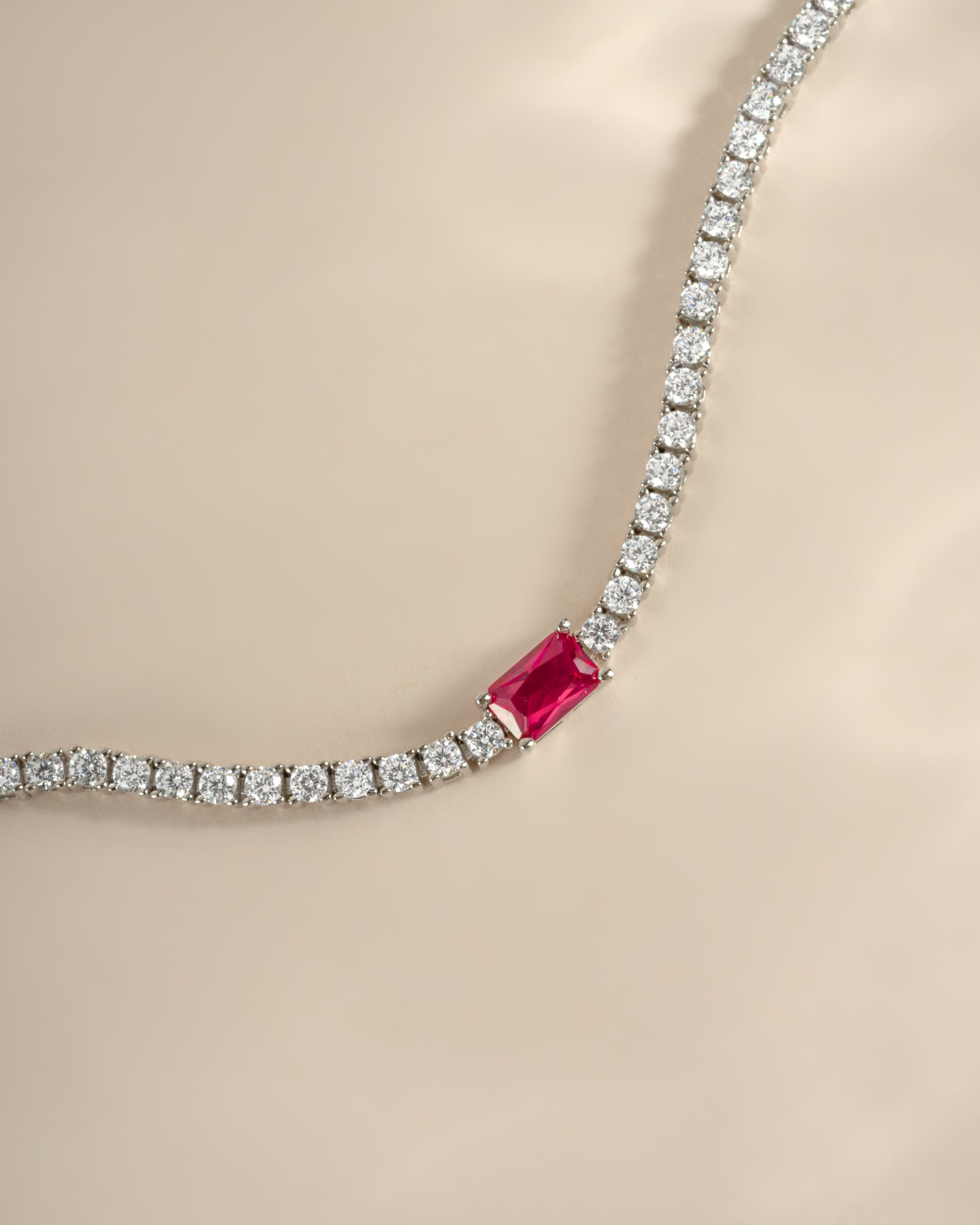 Close-up of Sami Jewels tennis bracelet featuring a ruby baguette charm and silver chain with intricate detailing.