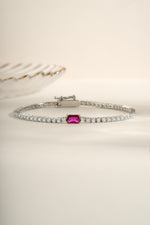 Silver tennis bracelet featuring a Ruby baguette charm, elegant jewelry piece by Sami Jewels.