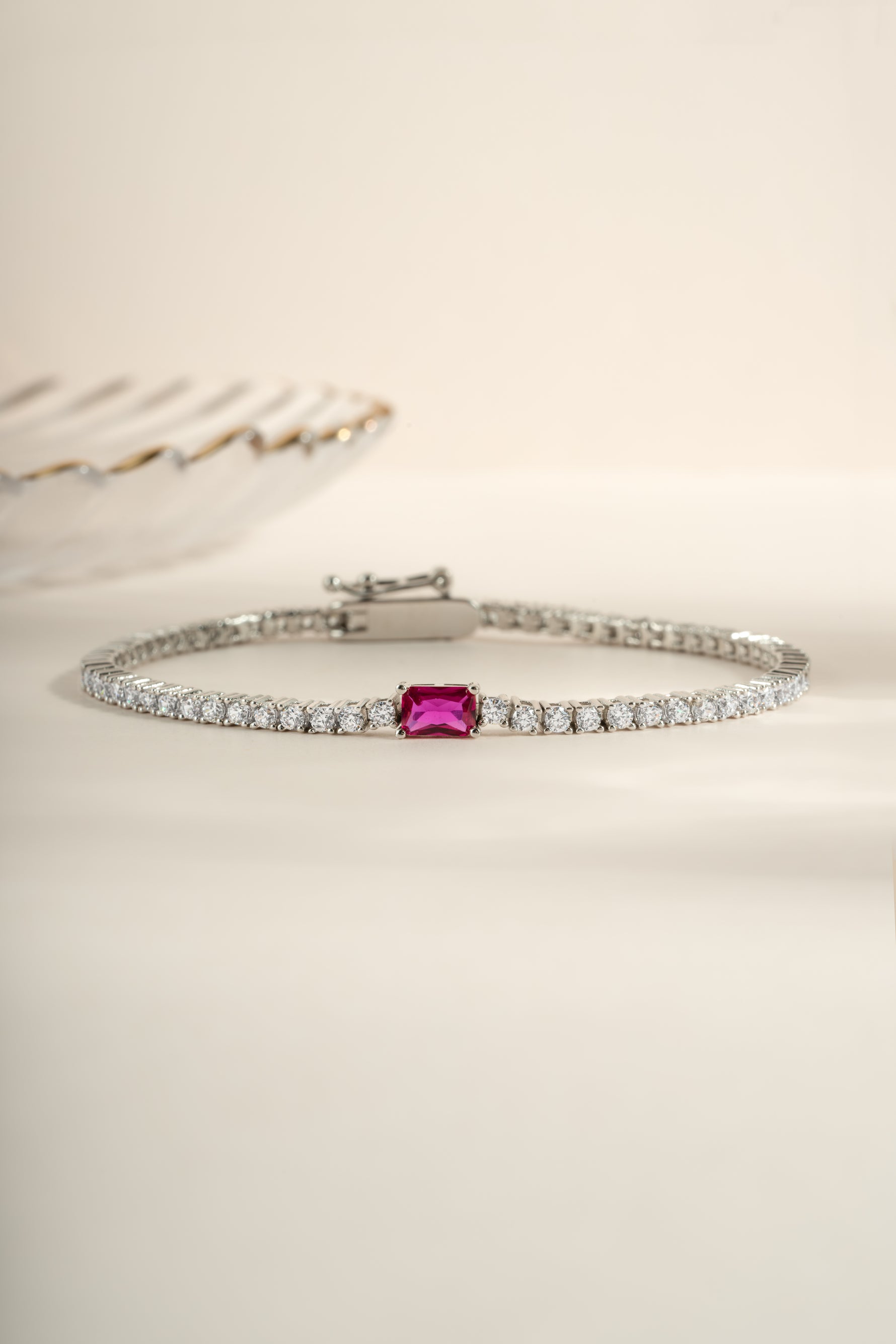 Silver tennis bracelet featuring a Ruby baguette charm, elegant jewelry piece by Sami Jewels.