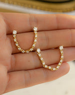 held on hand, a close up of a  pair of diamond-studded gold earrings for Double piercing
