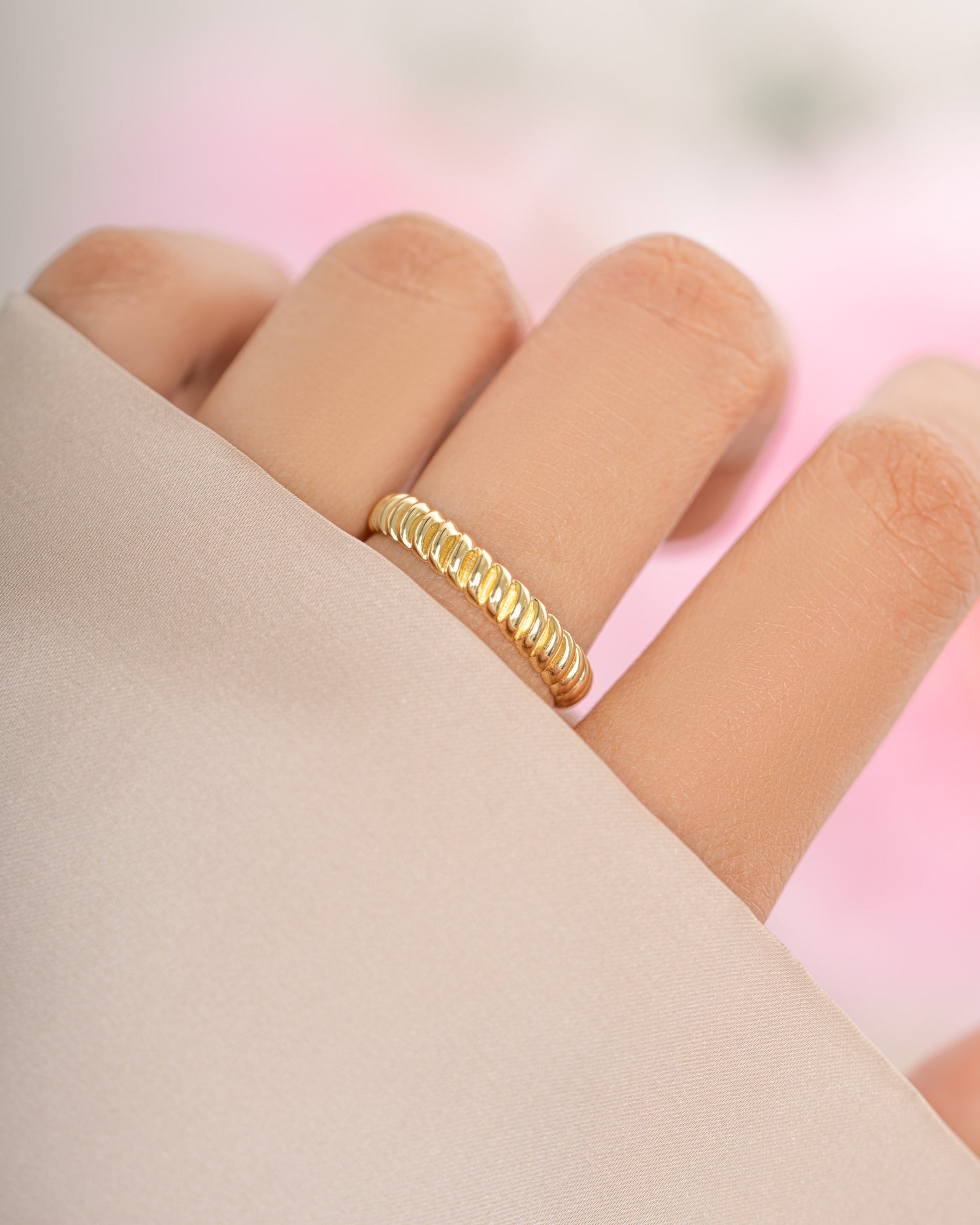 Gold textured stacking ring from Sami Jewels, featuring a detailed, layered design on a model's finger.