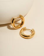 Gold stainless steel SS hoops earrings from Sami Jewels, thick huggie design with waterproof finish, angled view.