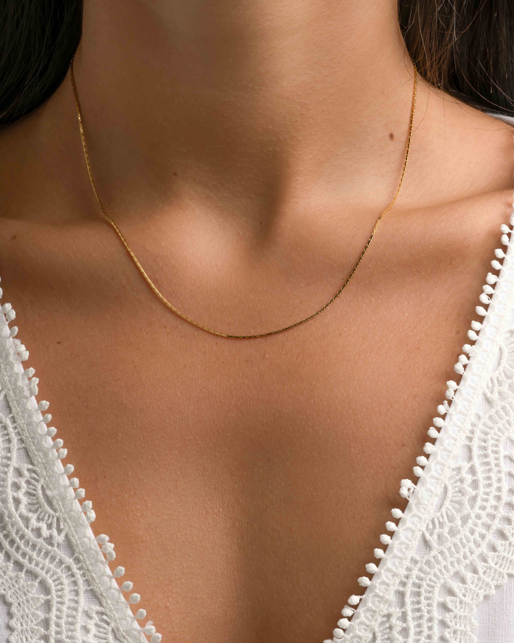 Gold thin chain necklace by Sami Jewels, close-up of delicate jewelry worn around the neck.