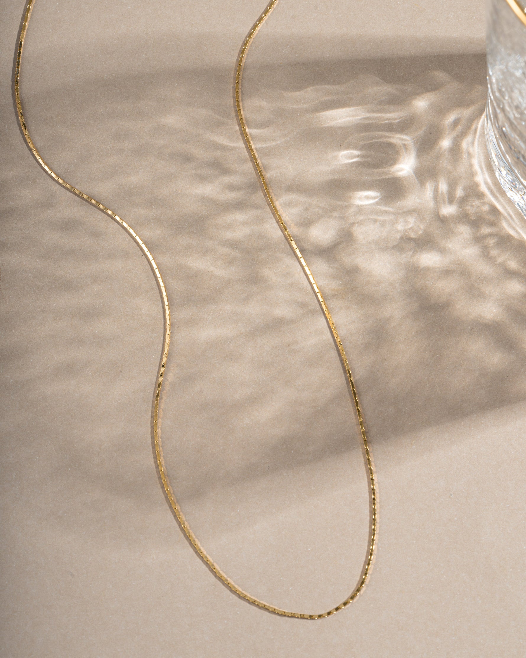 Gold thin chain necklace from Sami Jewels, close-up of delicate, lightweight jewelry on a neutral background.