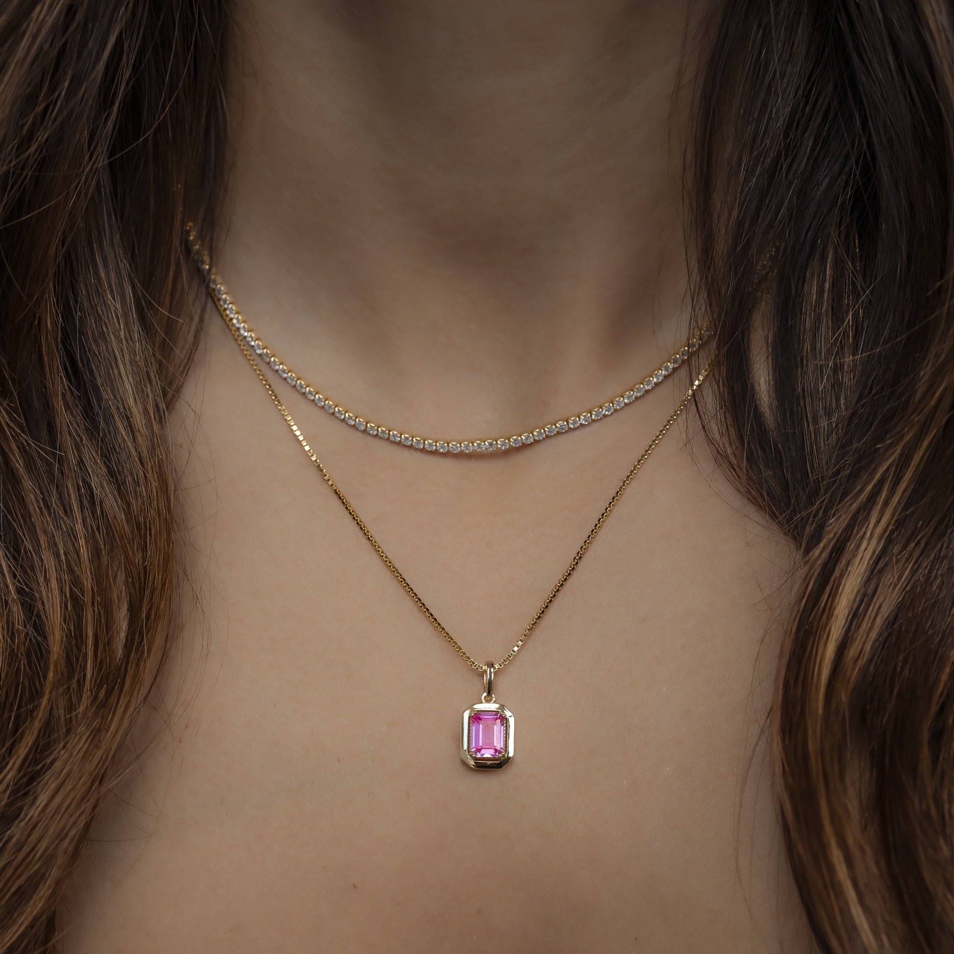 model wearing gold thin tennis necklace and pink pendant necklace stack