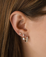 Gold Tiny CZ 3 Stone Stud Earrings by Sami Jewels, close-up view of sparkling cubic zirconia stones on classic studs.