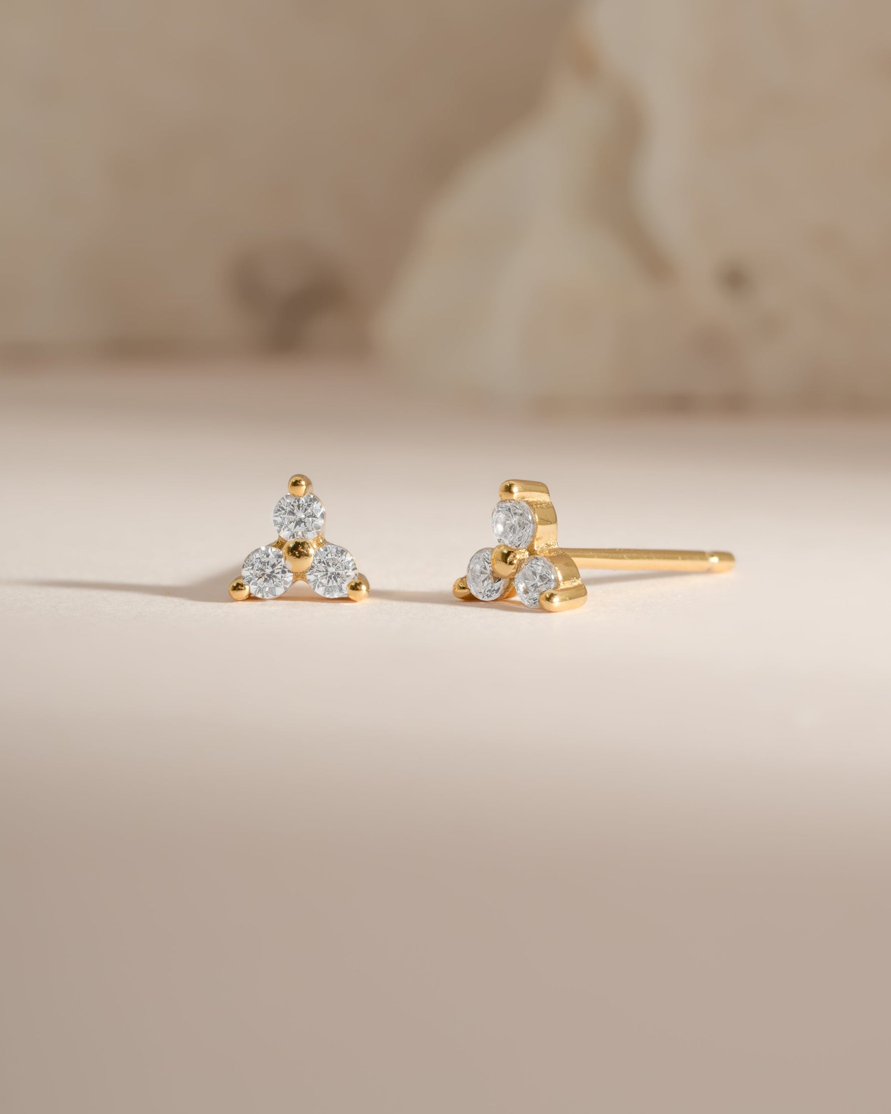 Gold three-stone CZ stud earrings by Sami Jewels, front view showing sparkling cubic zirconia stones in a classic stud design.
