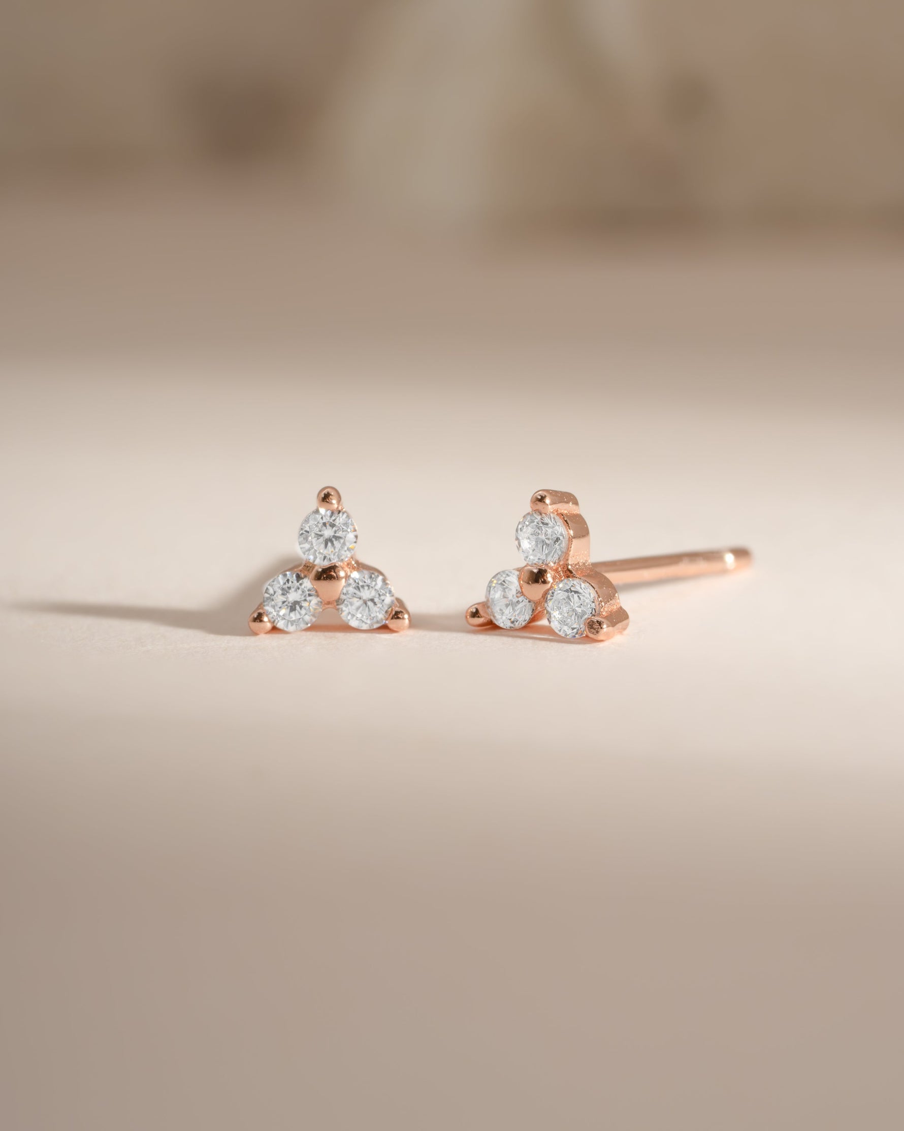 Rose gold three-stone CZ stud earrings by Sami Jewels, featuring sparkling cubic zirconia gemstones in a classic setting.