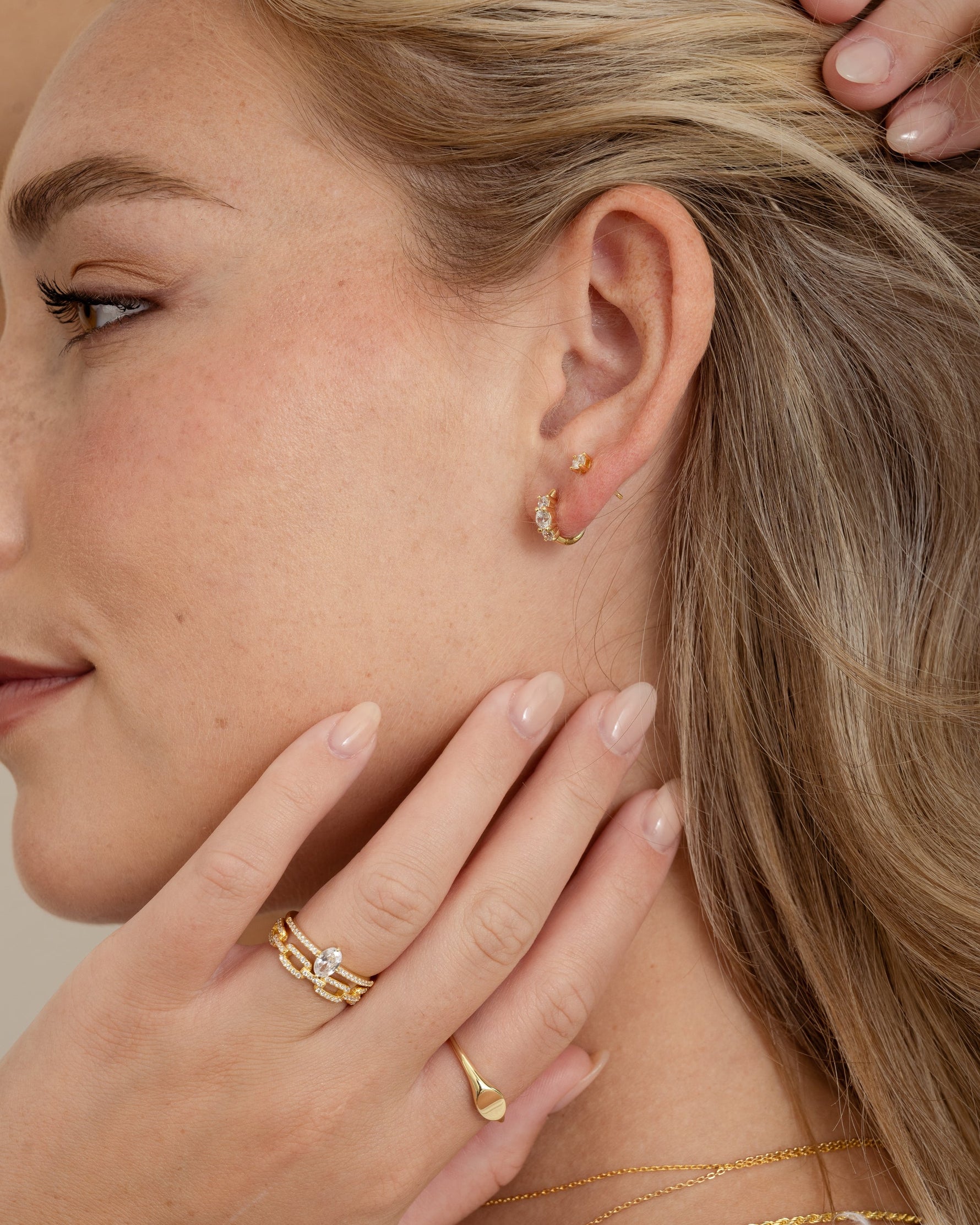 gold three stone huggie earring on model with gold jewelry