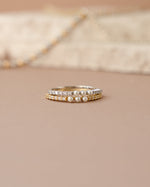 three stone pearl ring in gold and sterling silver stacked on top of eachother on a simple background