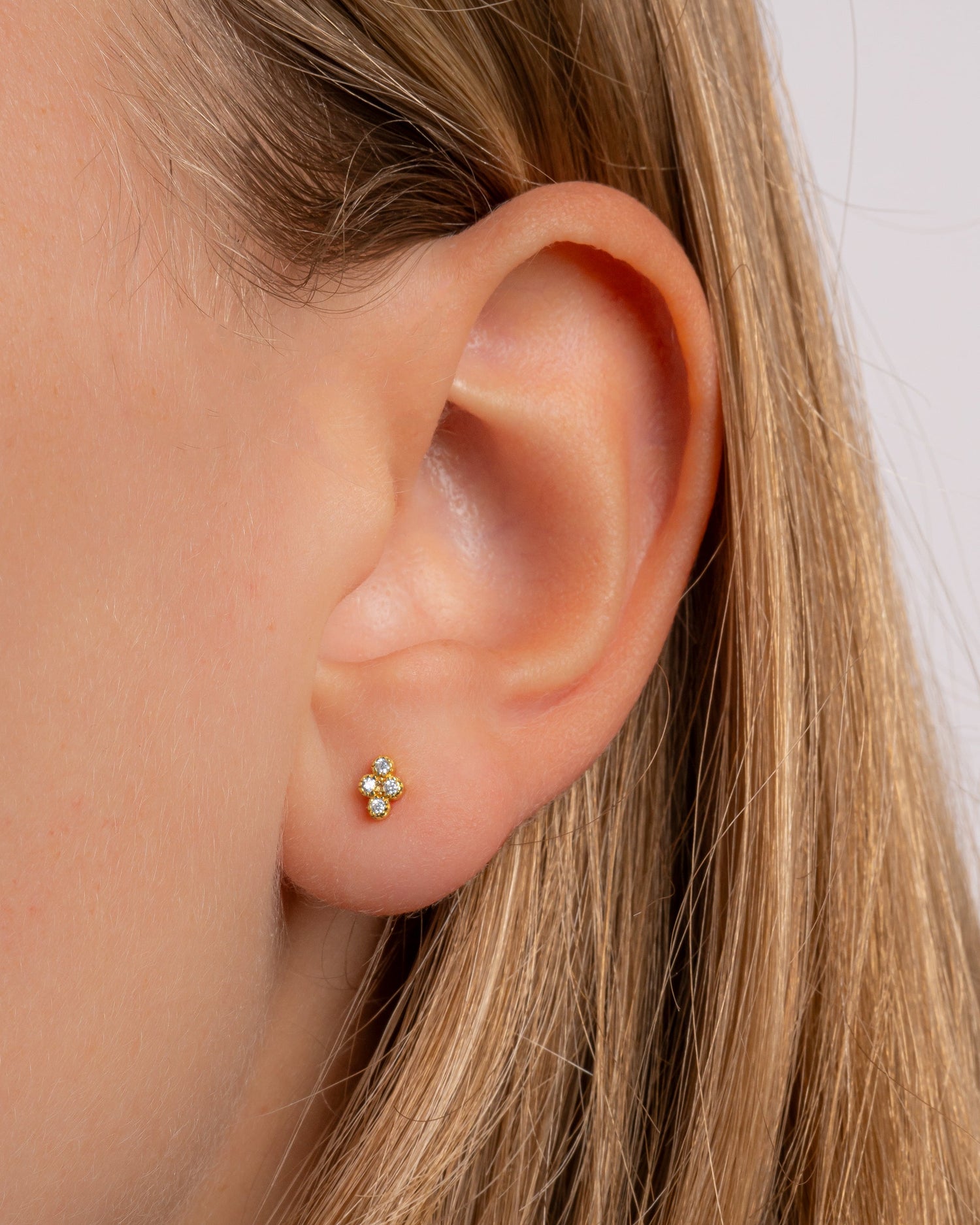 Gold Sami Jewels Tiny 4 Stone CZ Stud Earrings shown on a model, featuring sparkling cubic zirconia stones in a classic stud design.
