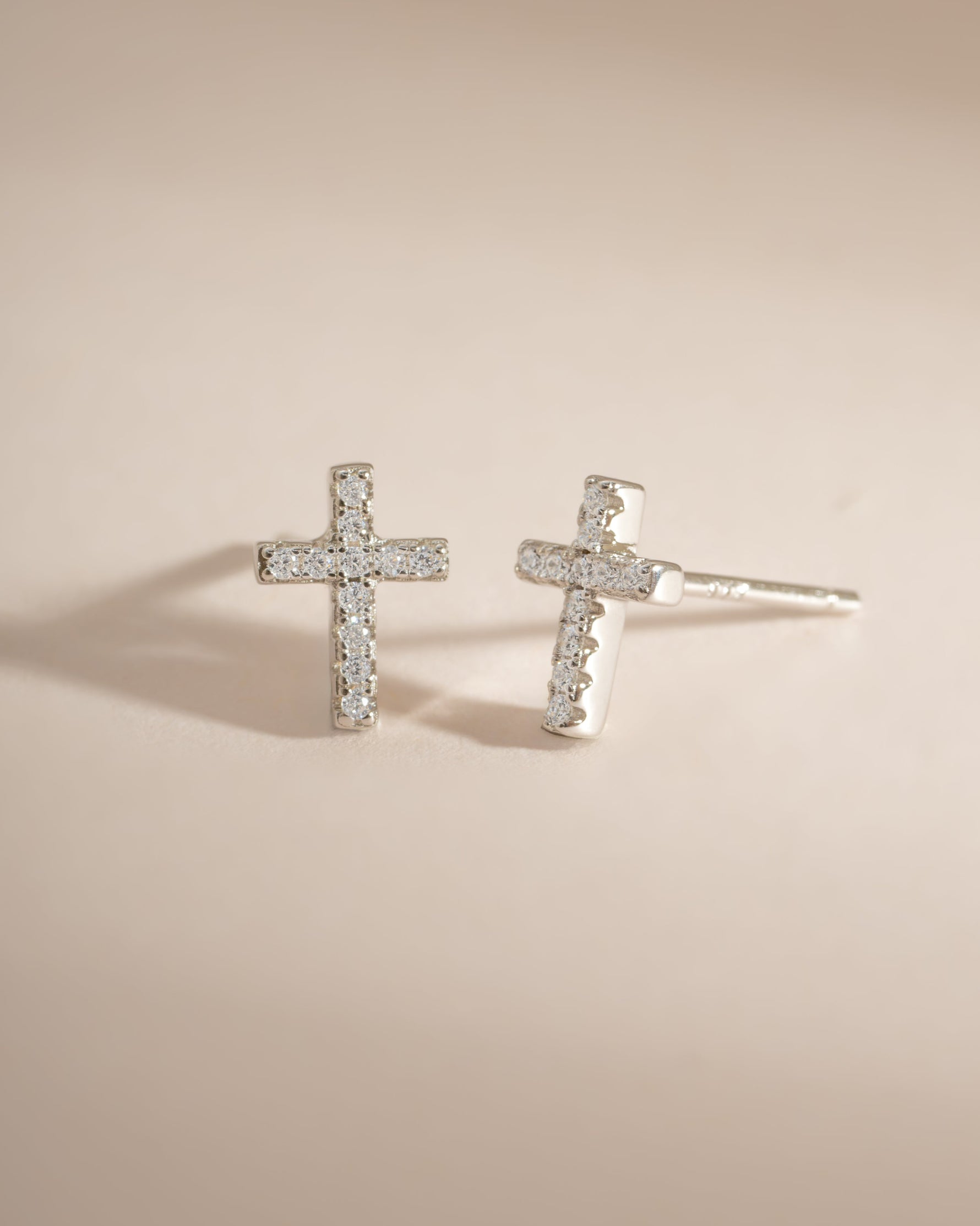Sterling silver tiny cross stud earrings by Sami Jewels featuring minimalist religious design and secure post-back closures.