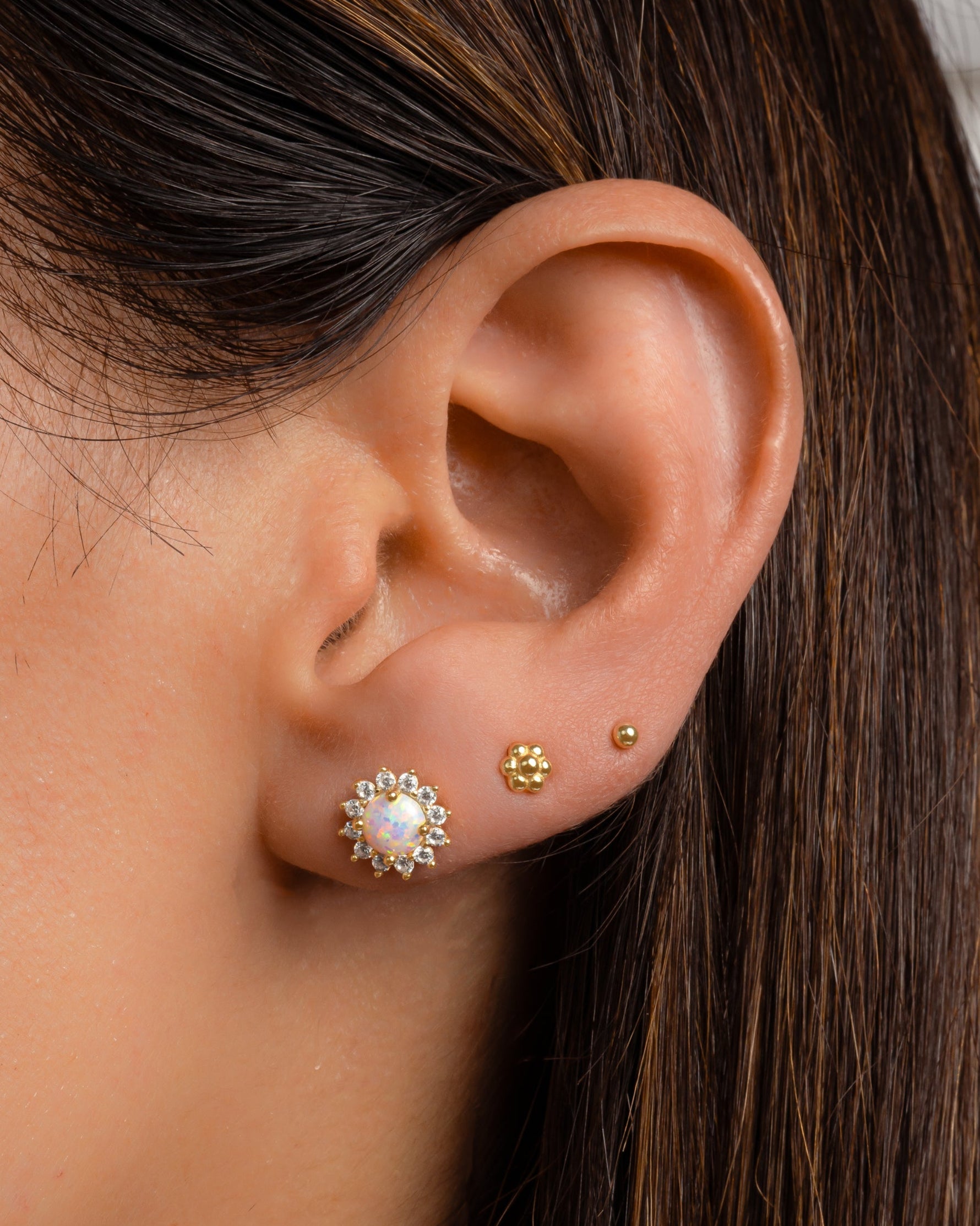 Gold tiny flower stud earrings by Sami Jewels featuring delicate floral design on a model.