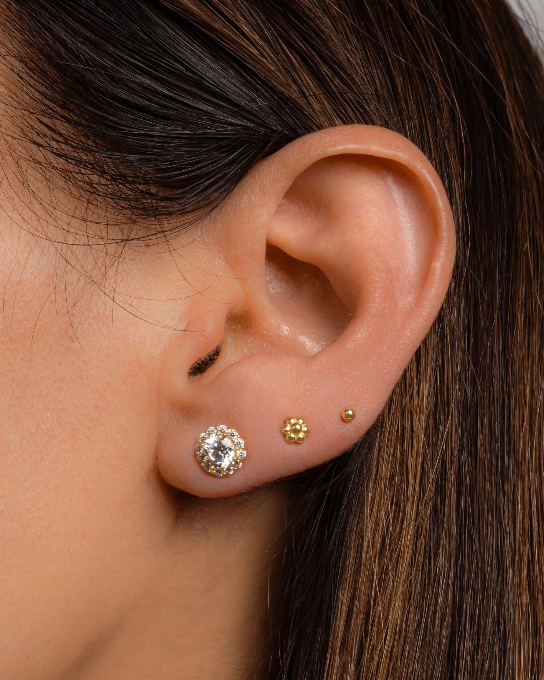 Gold tiny flower stud earrings by Sami Jewels worn on a model, showcasing delicate floral jewelry design.