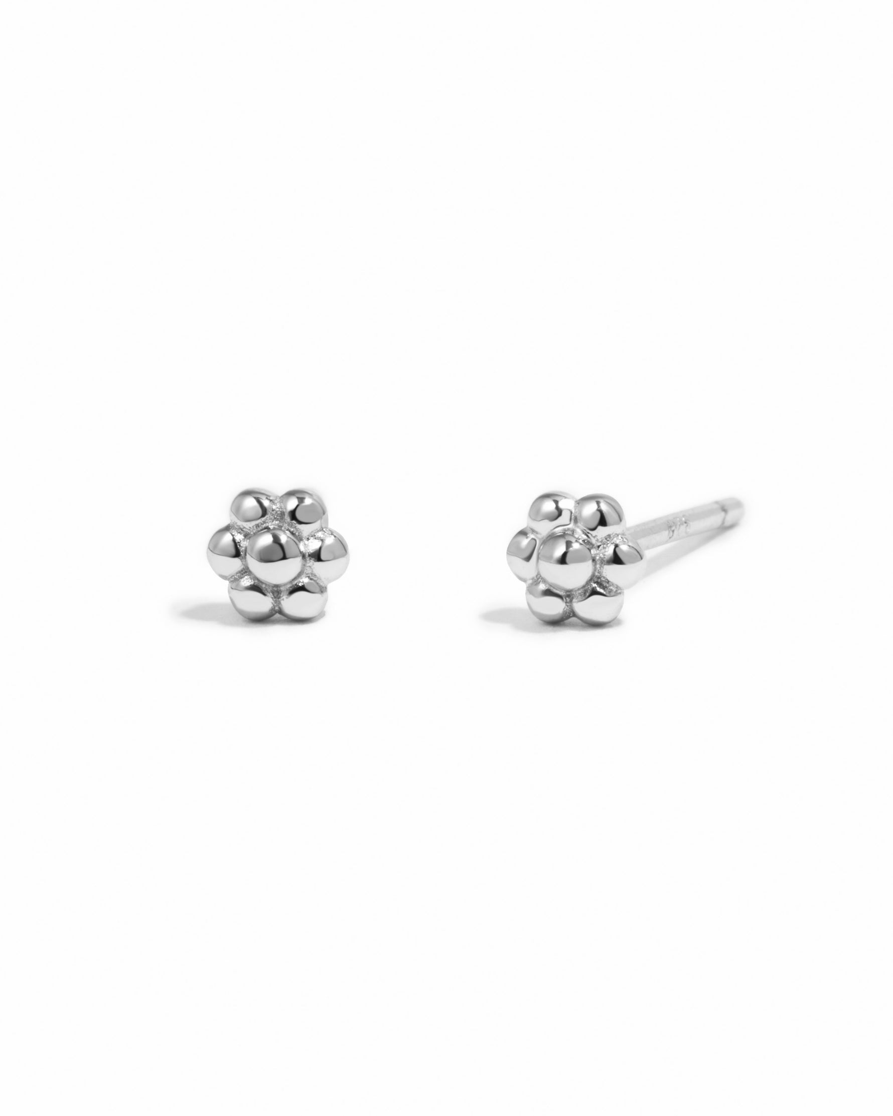 Sterling silver tiny flower stud earrings by Sami Jewels on a white background. Small, delicate flower design perfect for everyday wear.