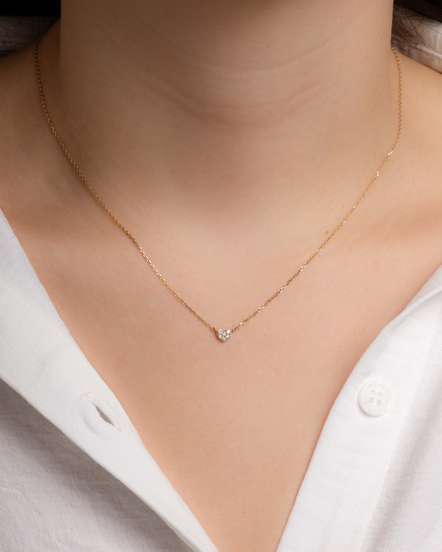 Gold Tiny Heart Necklace from Sami Jewels worn by a model, showcasing a delicate heart pendant on a fine chain.