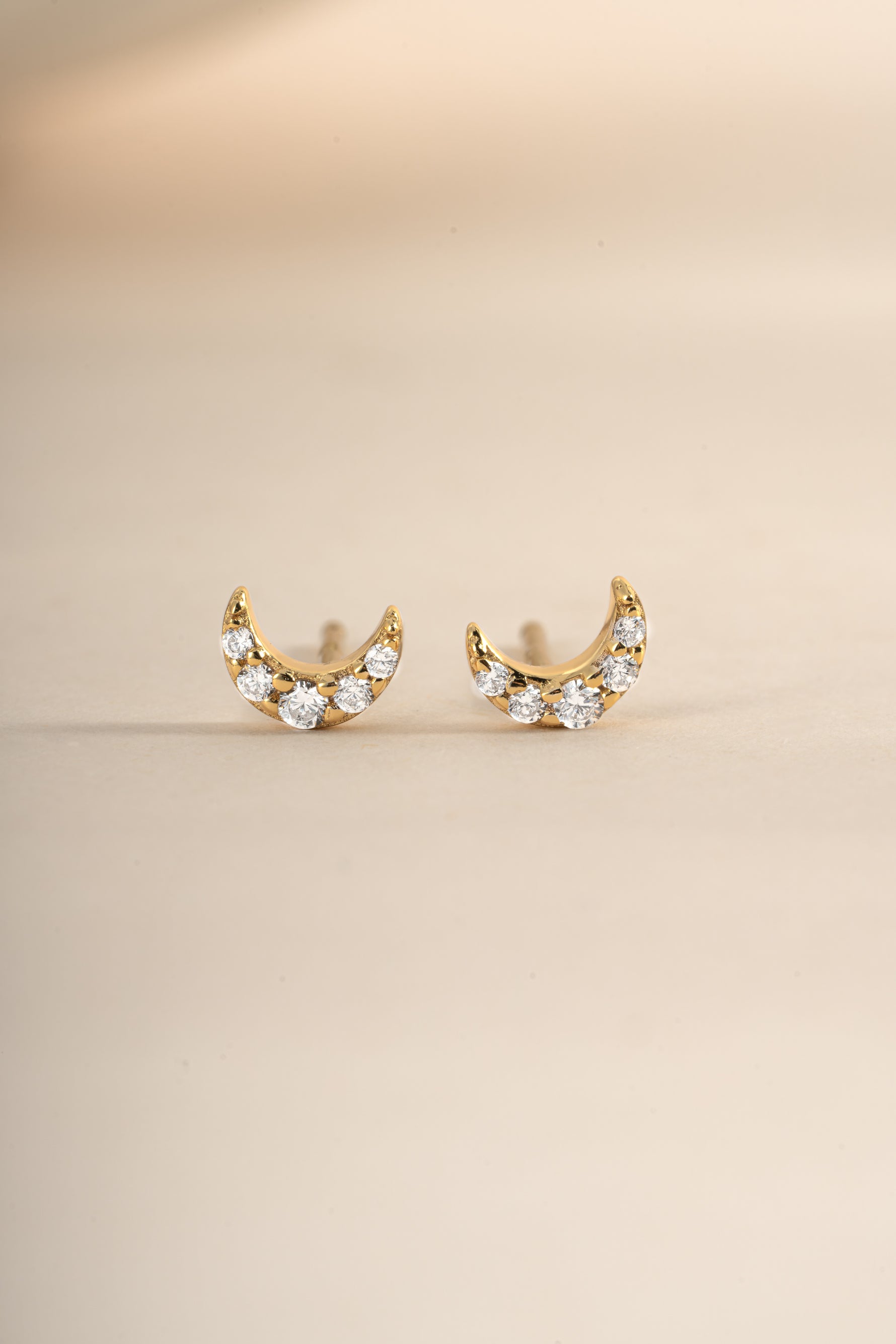 Gold tiny moon stud earrings from Sami Jewels with a close-up angled view, showcasing their small, celestial design.