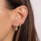 Model wearing gold chunky earrings on the first piercing stacked with minimalist diamond huggie earings and dainty diamond studs.