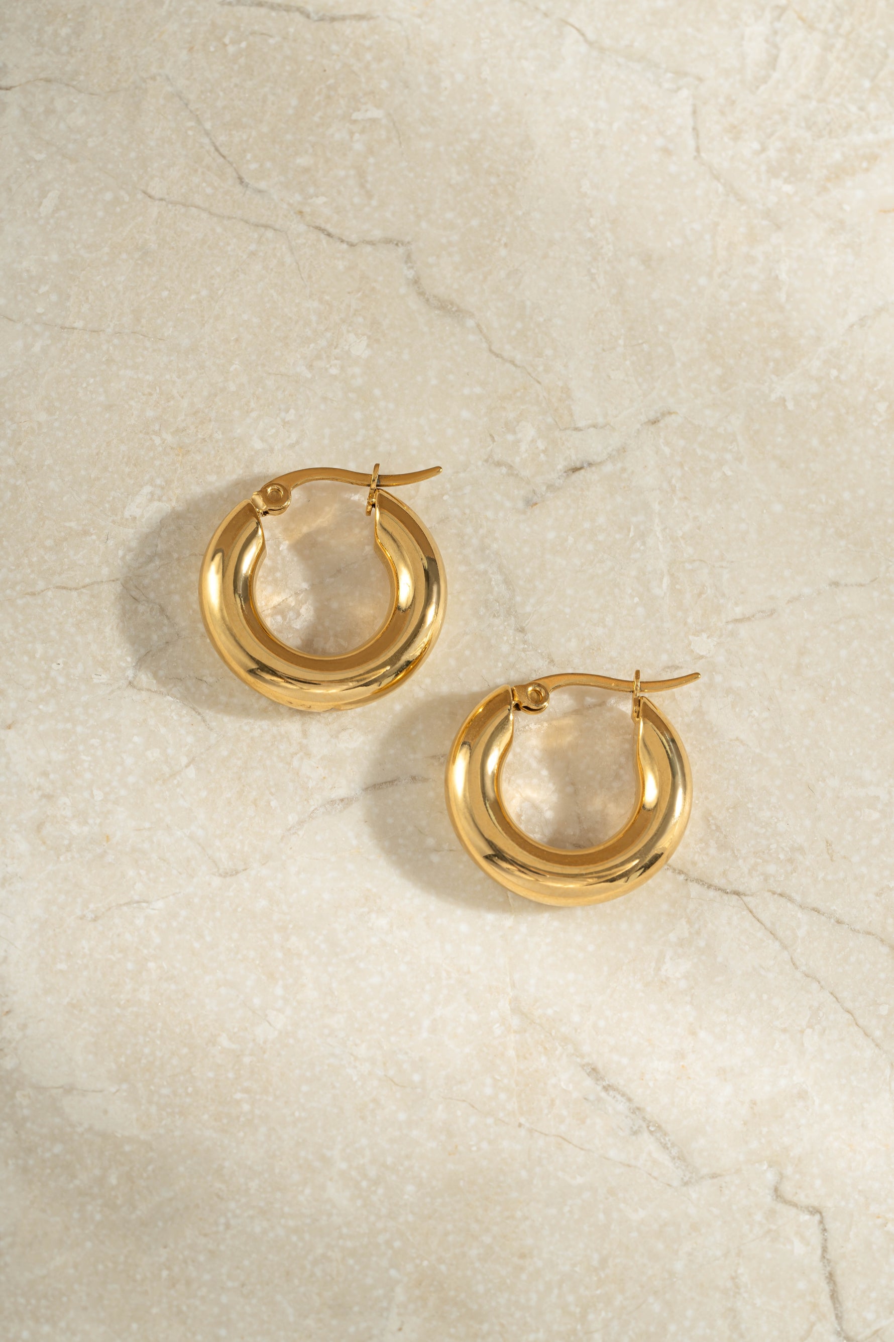 tube hoop earrings in gold on a simple background