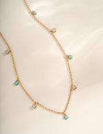 Close-up of Sami Jewels turquoise and CZ dangling charm necklace with gold chain, showcasing intricate design and vibrant colors.