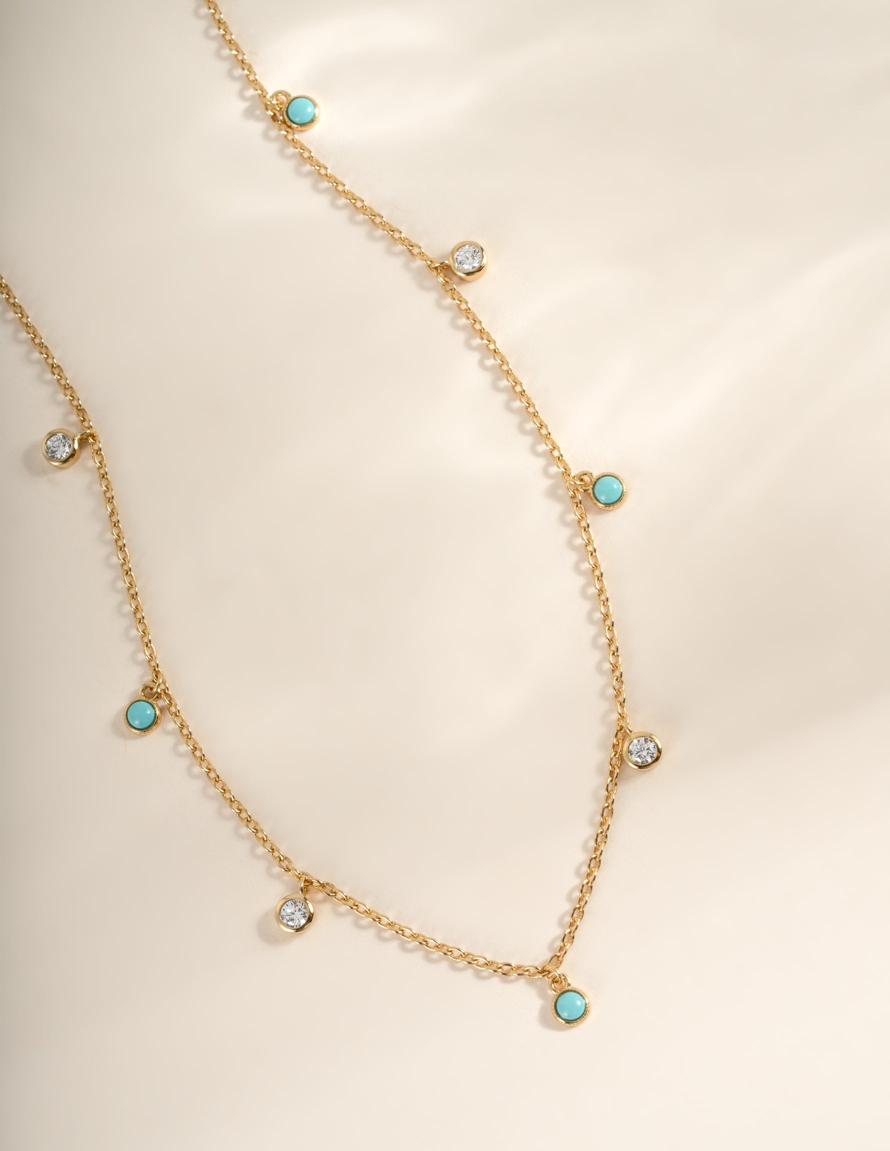 Close-up of Sami Jewels turquoise and CZ dangling charm necklace with gold chain, showcasing intricate design and vibrant colors.