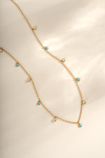 Turquoise and CZ dangling charm necklace in gold from Sami Jewels, featuring vibrant turquoise stones and sparkling cubic zirconia accents.