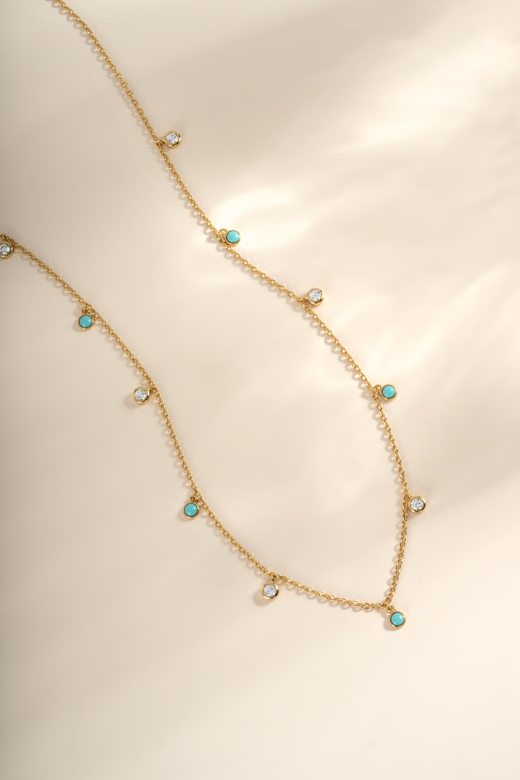 Turquoise and CZ dangling charm necklace in gold from Sami Jewels, featuring vibrant turquoise stones and sparkling cubic zirconia accents.