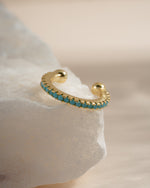 Close-up of a gold Sami Jewels turquoise ear cuff showing intricate design and vibrant turquoise stone detail.