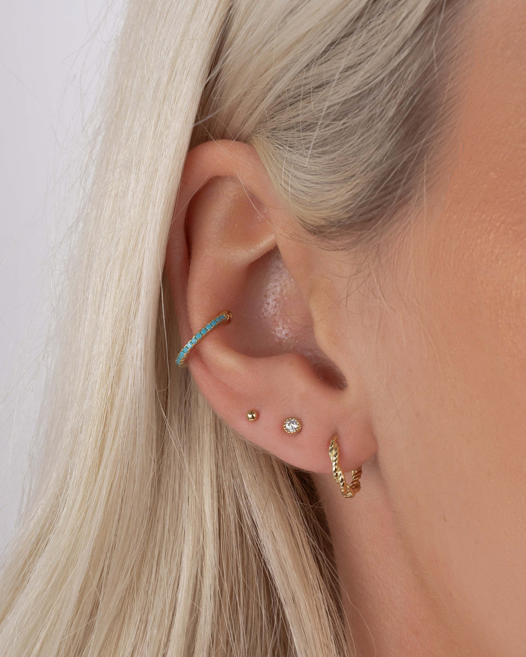 Turquoise ear cuff earrings by Sami Jewels, sterling silver with vibrant turquoise stones, worn on a model's ear.