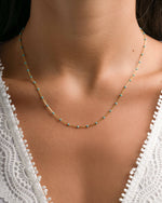 Turquoise enamel beaded necklace by Sami Jewels featuring vibrant turquoise beads and gold accents, worn by a model.