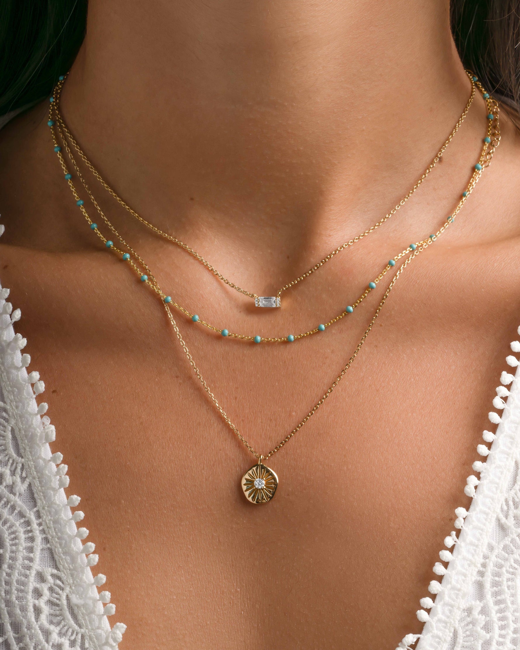 Turquoise enamel beaded necklace from Sami Jewels styled in a stack with gold accents on a model.
