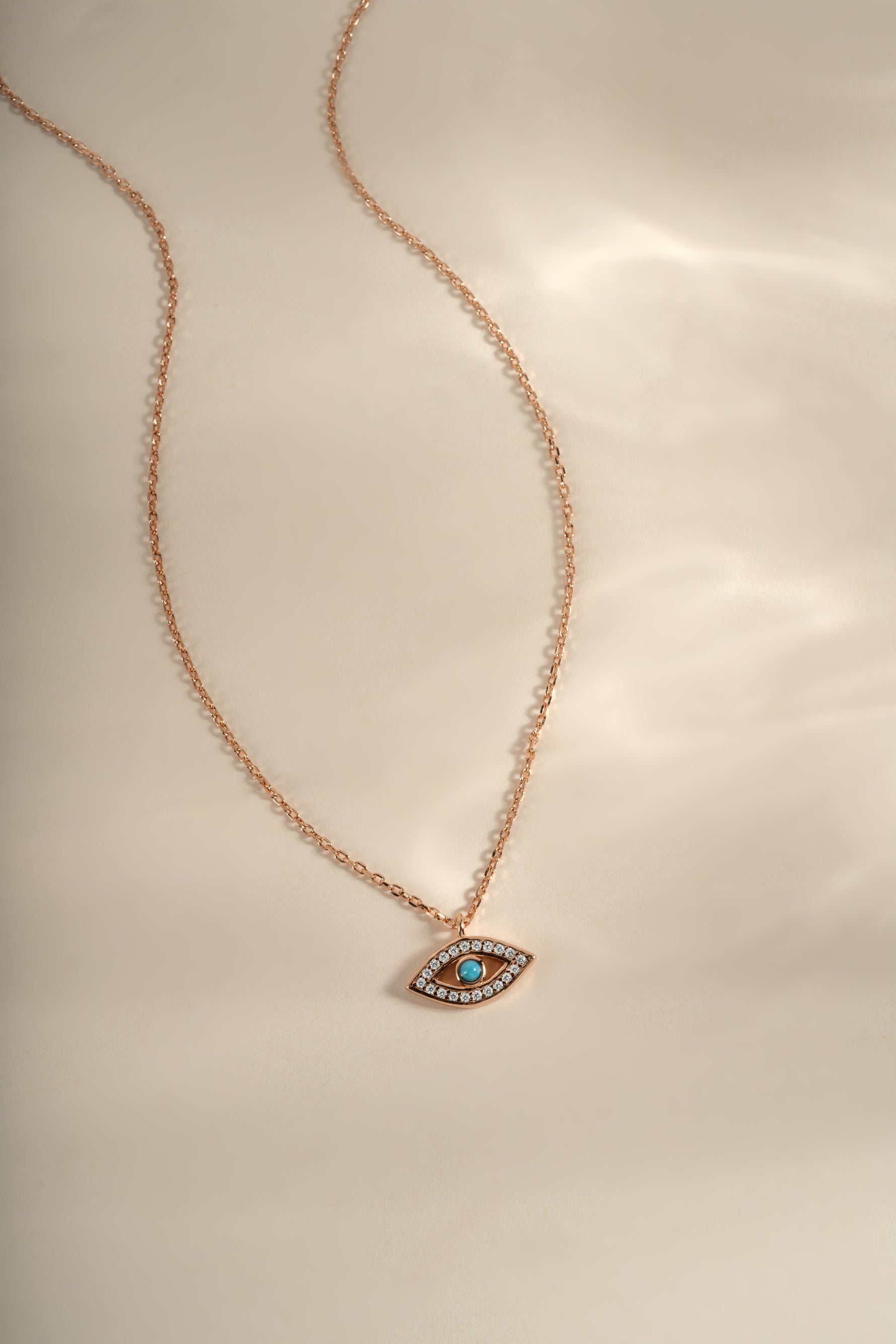 Turquoise evil eye necklace with rose gold chain from Sami Jewels, featuring a circular evil eye pendant with turquoise and gold accents.