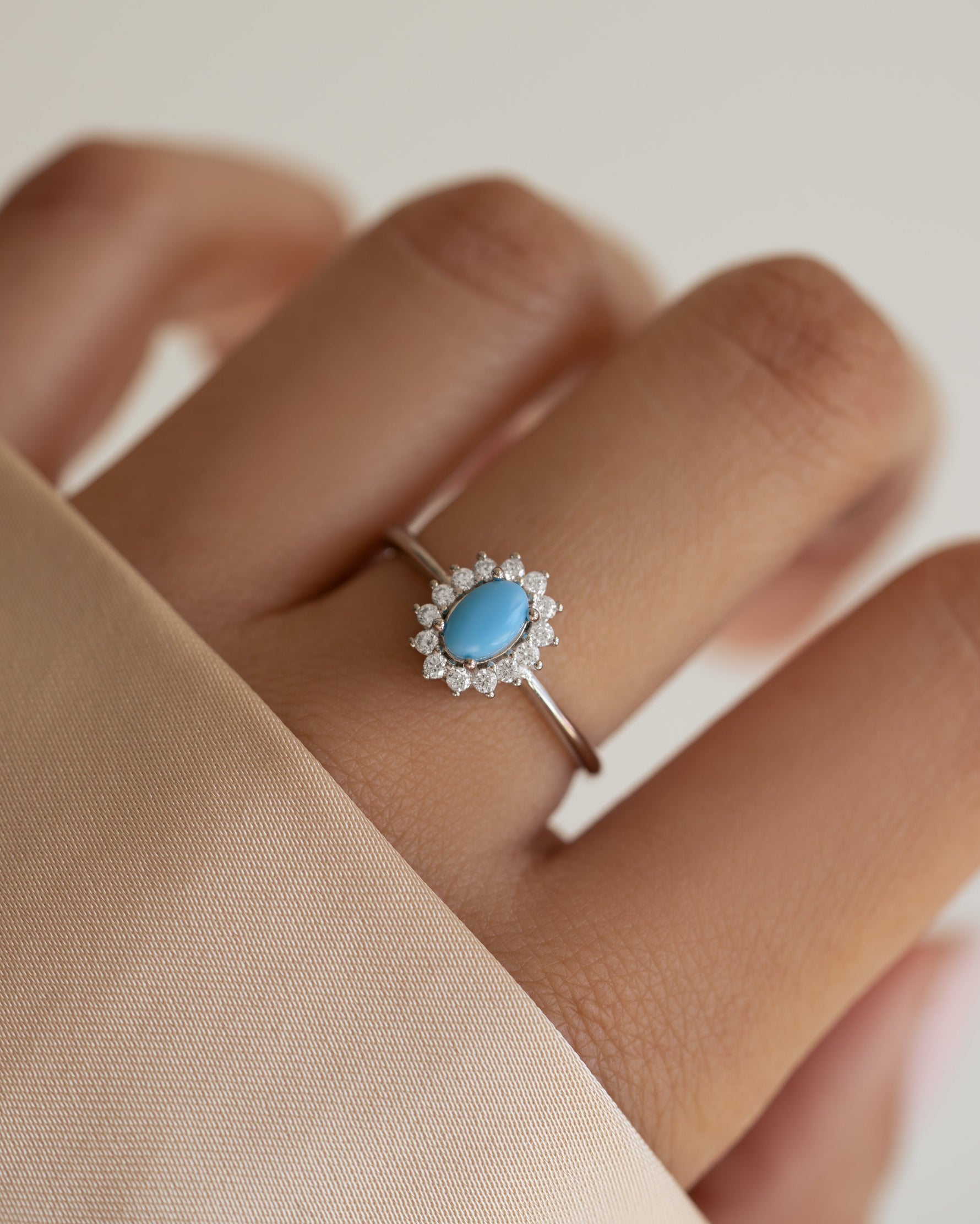 Sami Jewels Layla turquoise oval halo ring in sterling silver worn on a model's finger, showcasing intricate design and vibrant gemstone.