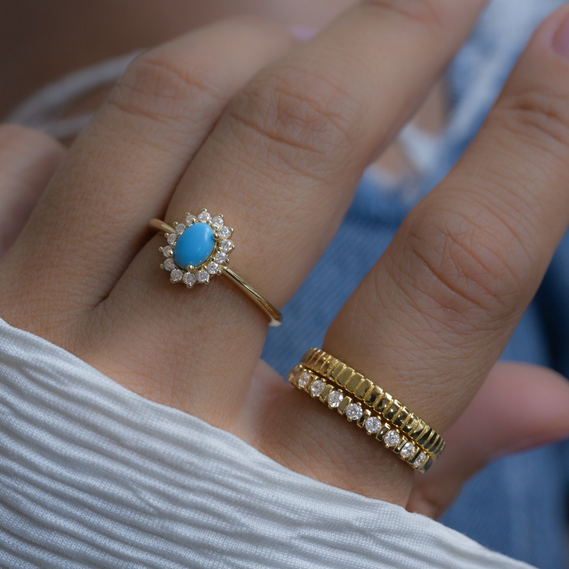 model wearing turquoise ring with halo on middle finger with a fluted cz ring and textured ring on index finger