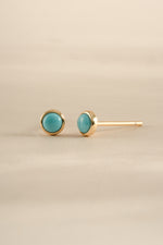 Gold angled view of turquoise stud earrings by Sami Jewels, showcasing vibrant turquoise stones and sleek gold settings.