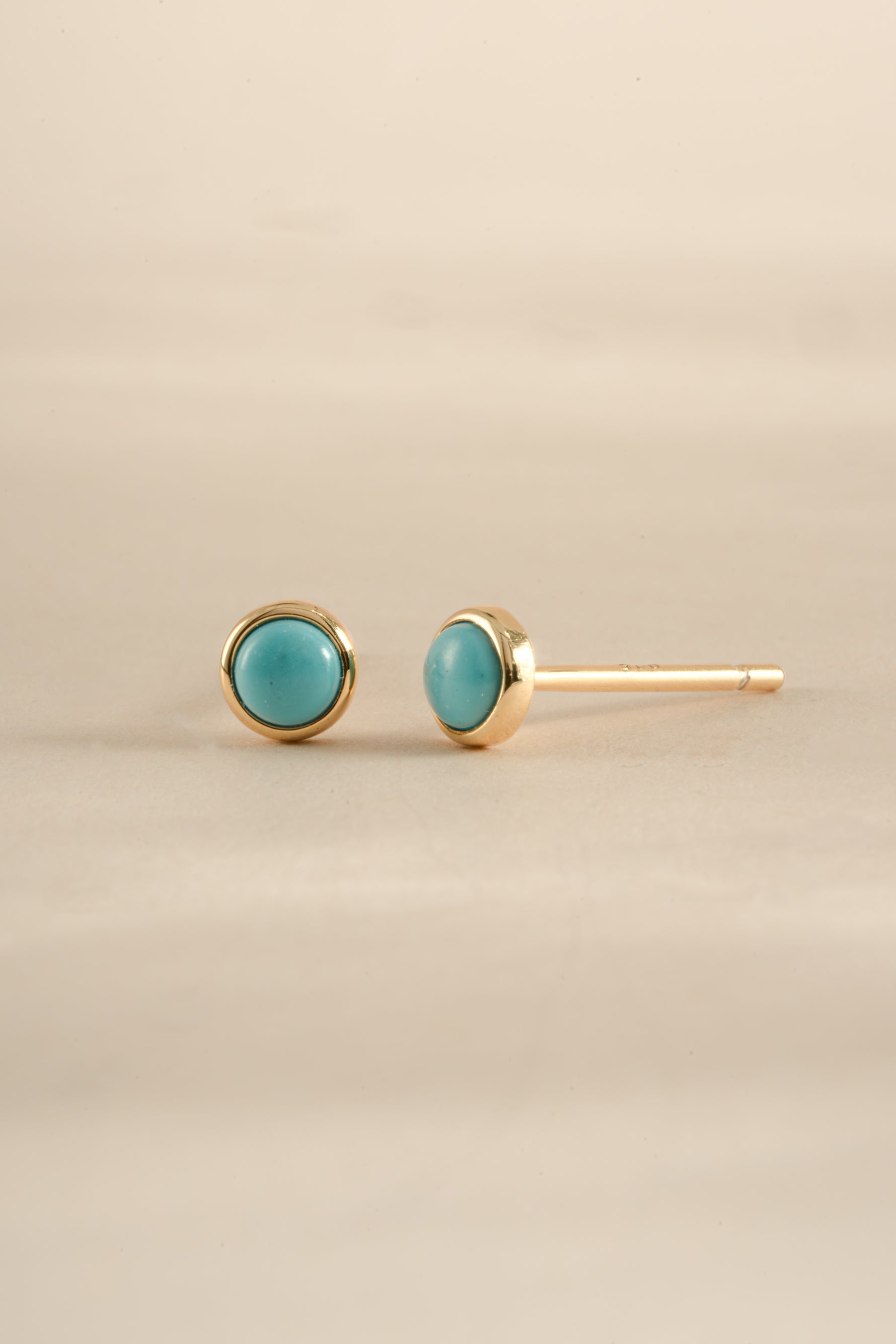 Gold angled view of turquoise stud earrings by Sami Jewels, showcasing vibrant turquoise stones and sleek gold settings.