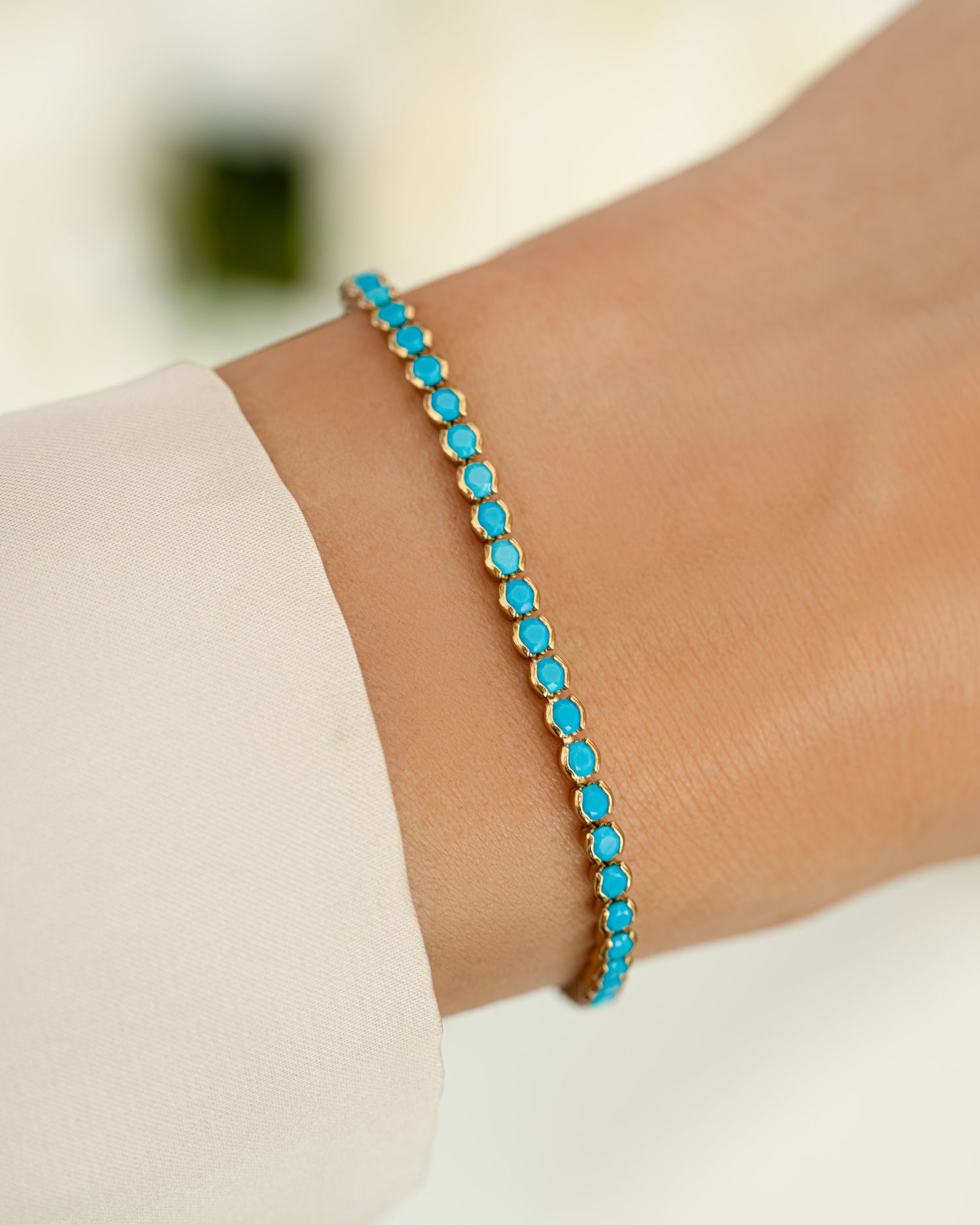turquoise tennis bracelet in gold on models wrist 