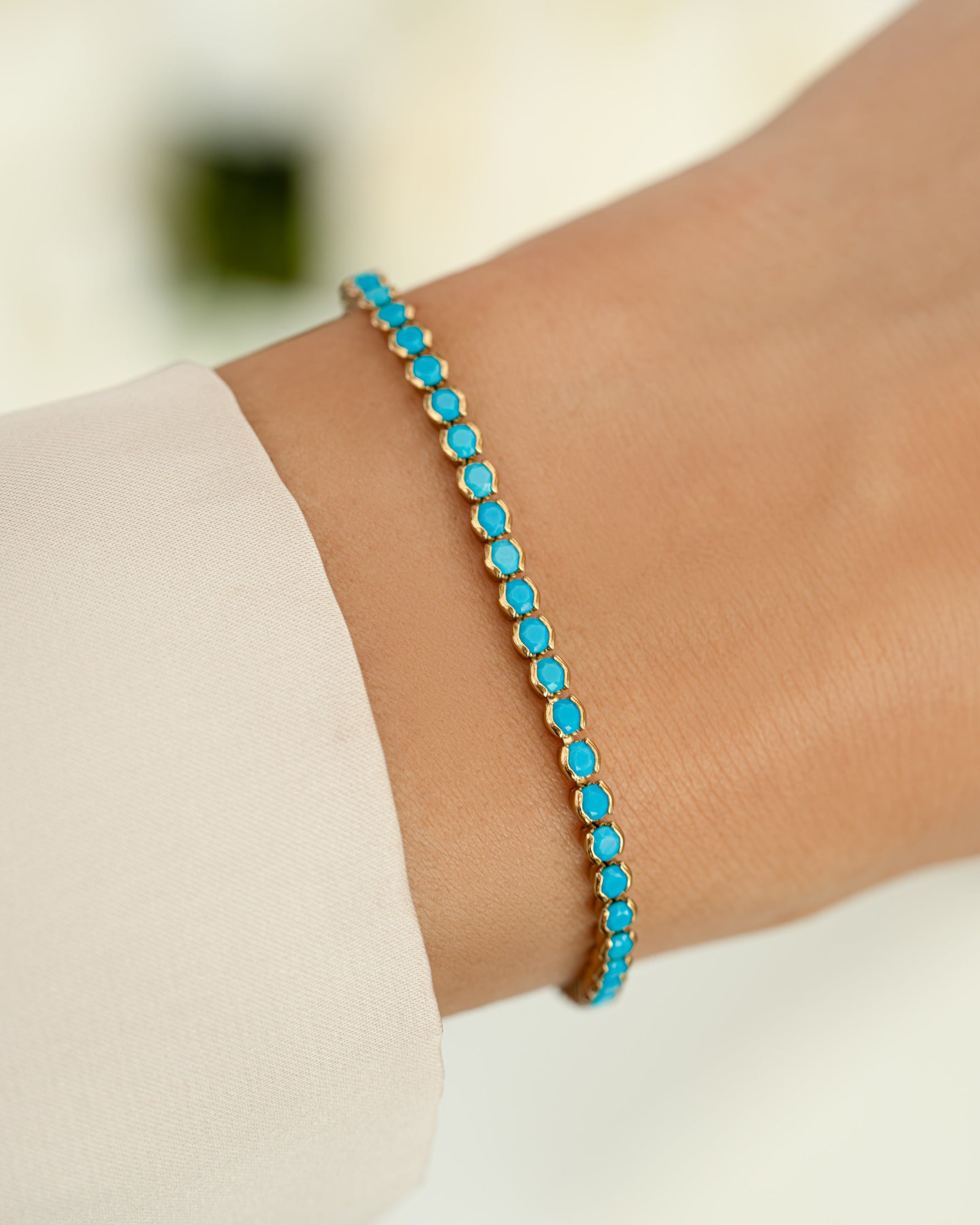 turquoise tennis bracelet in gold on models wrist 