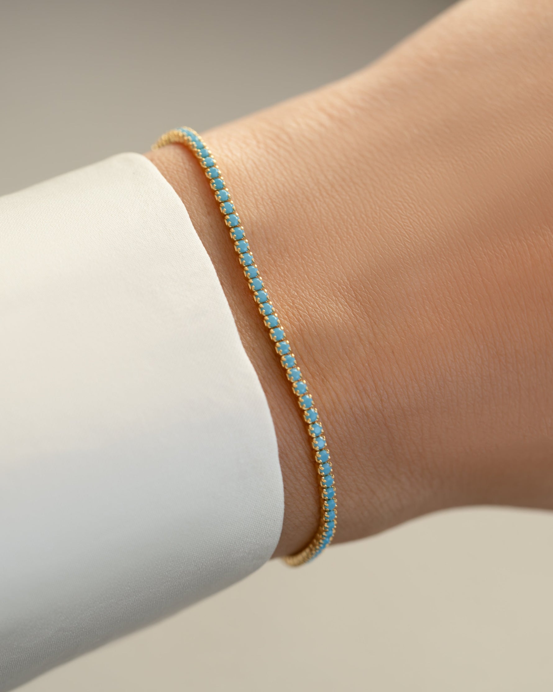 Turquoise tennis bracelet by Sami Jewels featuring gold accents, worn on a model's wrist for elegant jewelry styling.