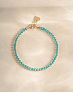 turquoise tennis bracelet in gold on a simple background